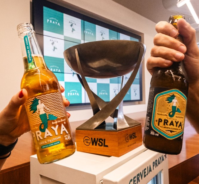 Cerveja Praya ao lado da taça de campeão mundial de surf, conquistada por Yago Dora