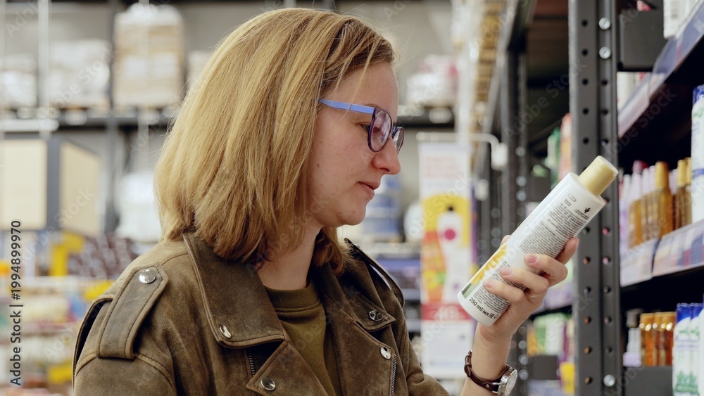 Uma mulher olhando o rótulo de um shampoo em um supermercado