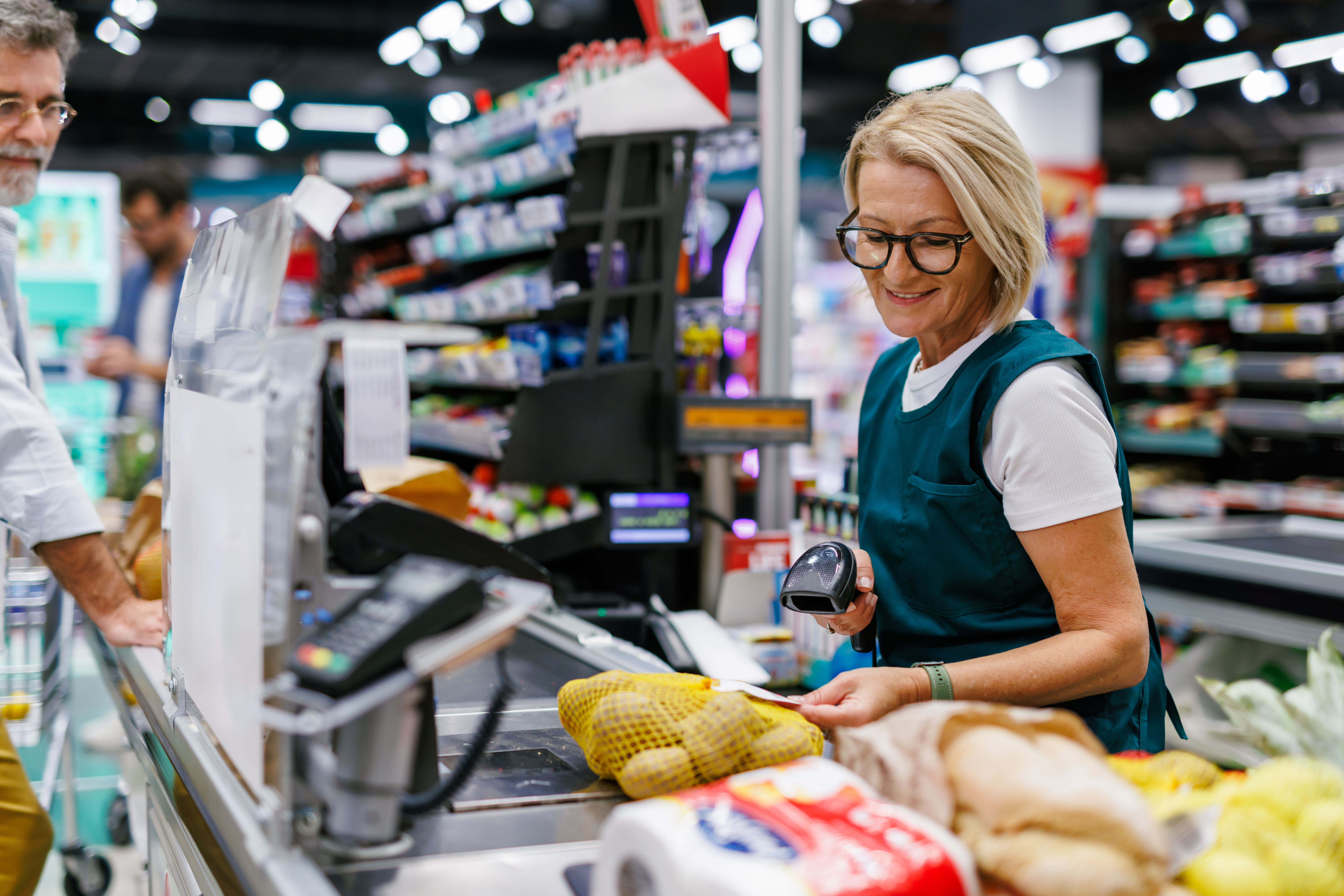 Funcionária de supermercado passando compras no checkout